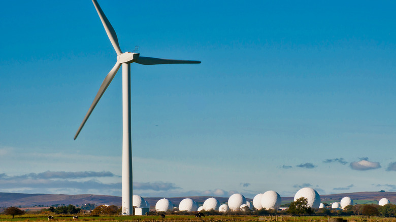 A wind turbine seen standing just beyond a military RAF base radar cluster