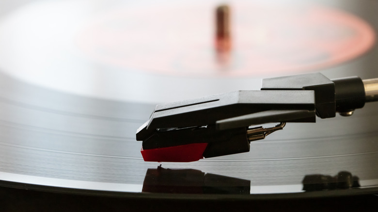 Closeup of a turntable cartridge over a vinyl record.