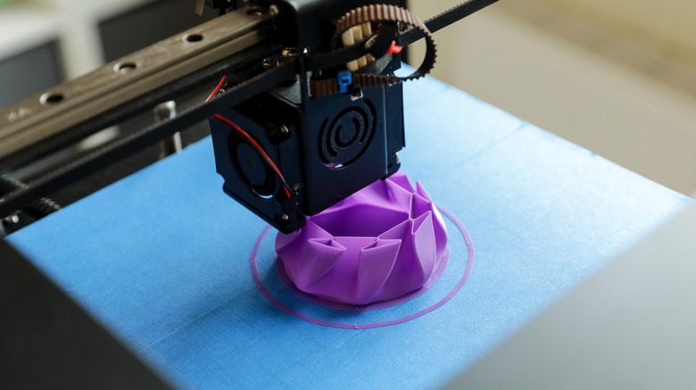 A 3d printer printing a prototype model out of purple plastic material