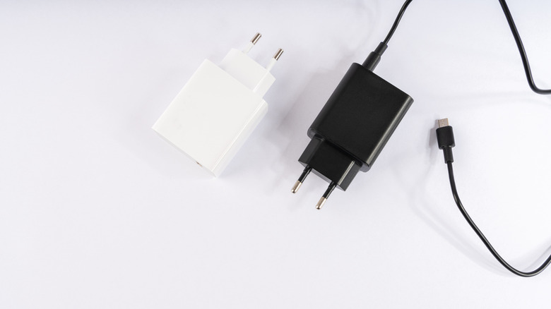 White adaptor, black adaptor, and charging cable with a USB-C plug on a white surface