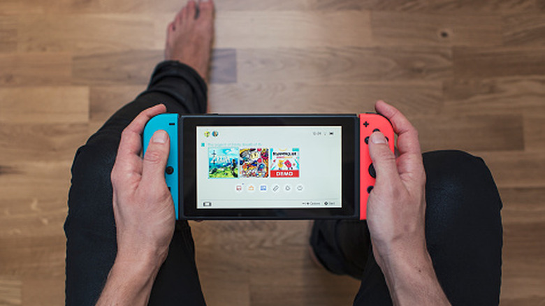A shot from above of a person's hands holding a neon coloured Nintendo Switch