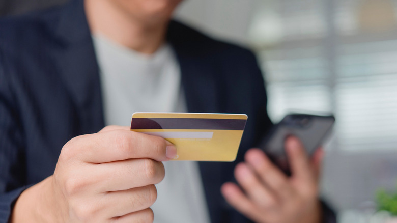 A person holding a phone and credit card