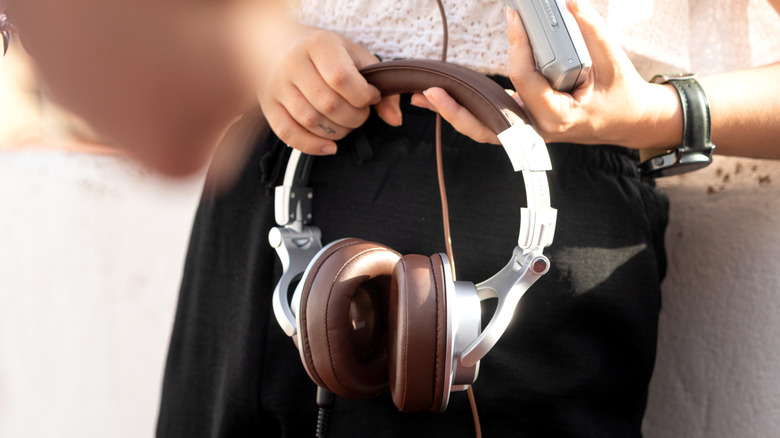 Close up of someone holding wired headphones connected to a device.