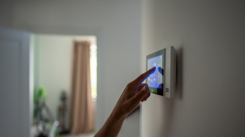 A person using a smart thermostat.