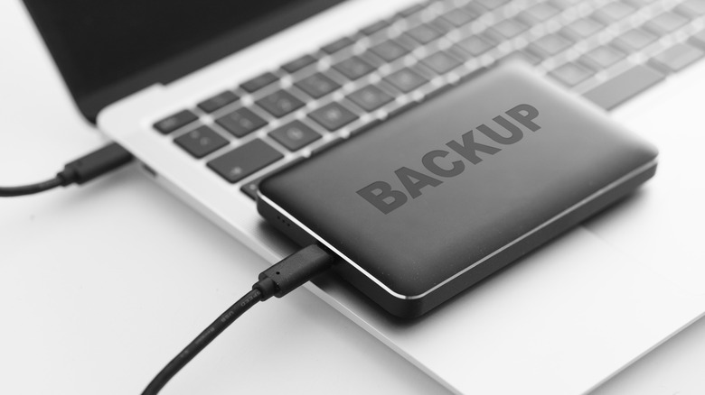 An external hard drive plugged into a laptop, with the word 