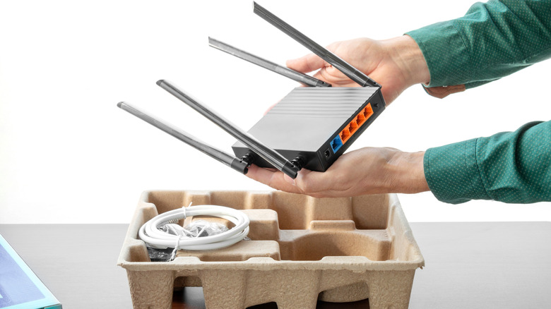 Someone unpacking a new wireless router from the box.