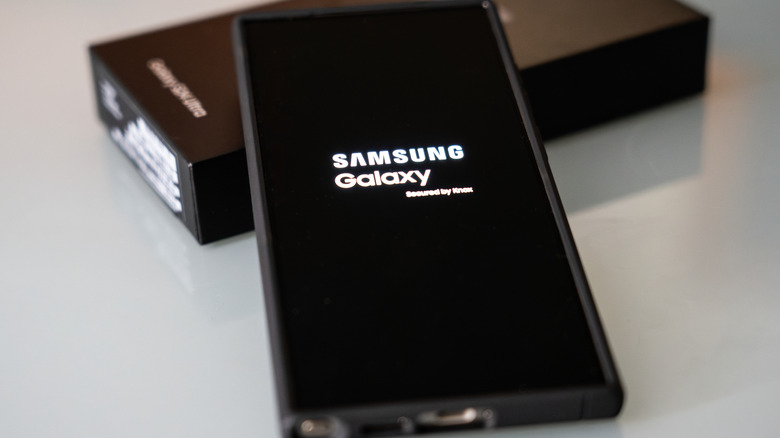 Samsung Galaxy phone showing the startup screen beside its retail box.