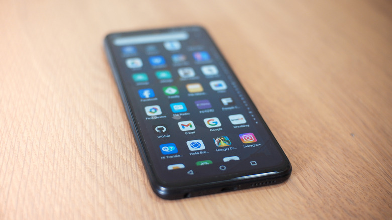 A collection of Android apps on a smartphone laying on a beige surface.