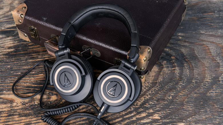 A pair of Audio-Technica headphones sitting on a table, leaning against a briefcase.