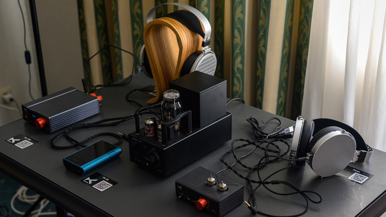 High-end headphones sitting on a display table accompanied by high-end headphone amplifiers and DACs