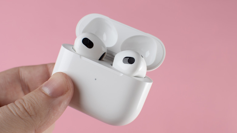 Person holding Apple AirPods in their charging case.