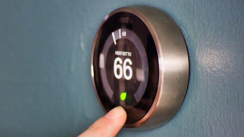 Google Nest thermostat mounted on a wall being adjusted