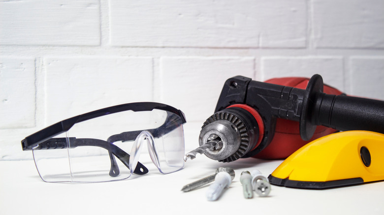 Drill, safety glasses, and anchors and screws for wall hanging projects.