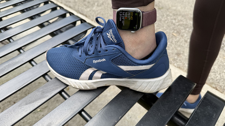 A woman's foot on a bench with an Apple Watch around the ankle.