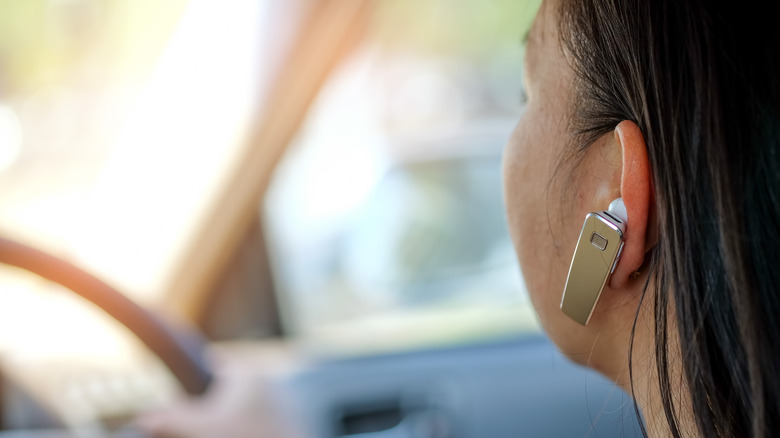 Close-up of a Bluetooth headset in a woman's ear while she's driving.