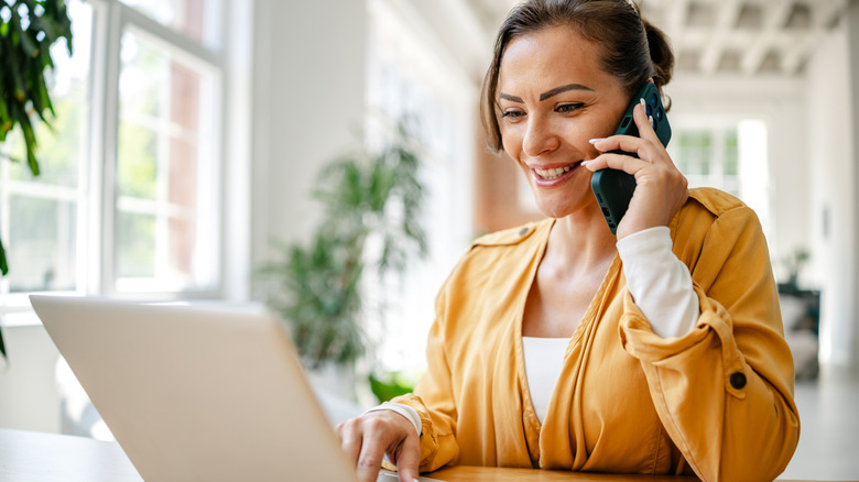 Person using computer while on phone