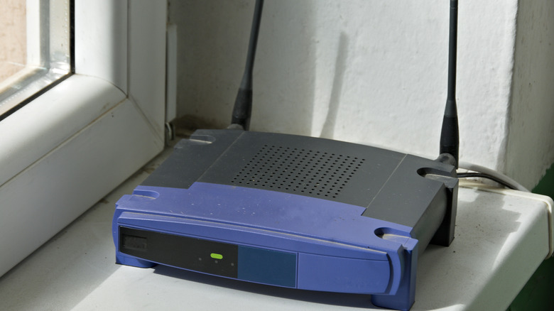 Close up of older blue and black Linksys router on a windowsill.