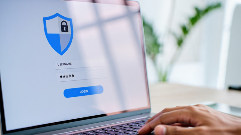 A hand typing router password on laptop