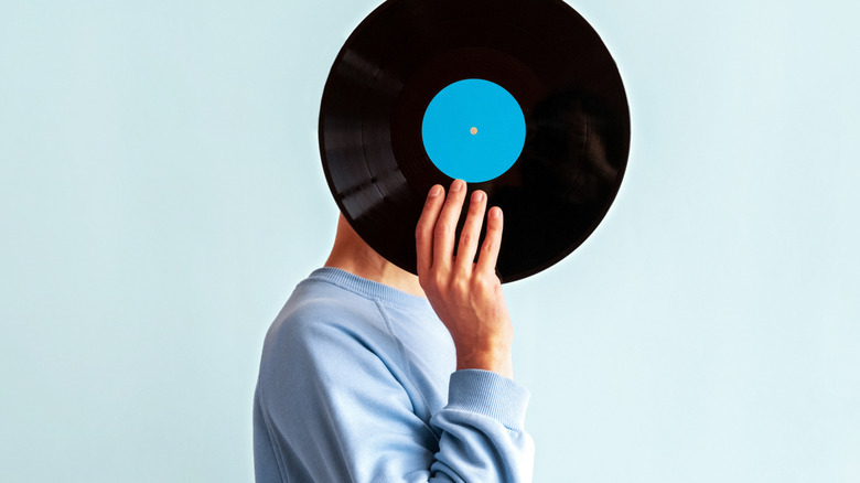 A CD resting on top of a vinyl record on a white background.