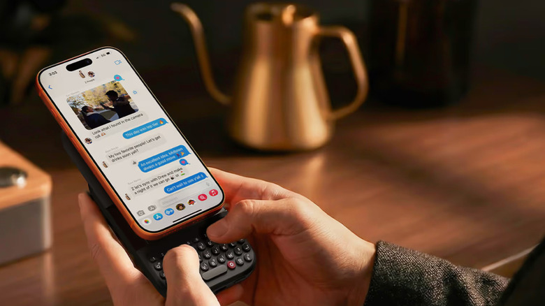 Person typing on Clicks physical keyboard attached to an iPhone