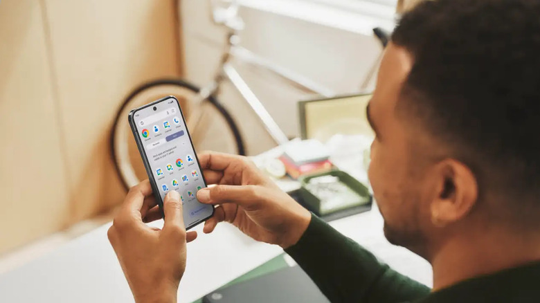 Person holding Android phone with app drawer on the screen