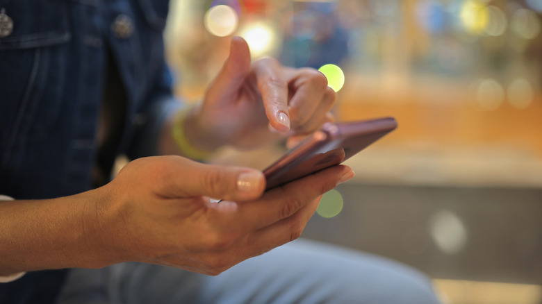 Phone held in hand as someone types with software keyboard