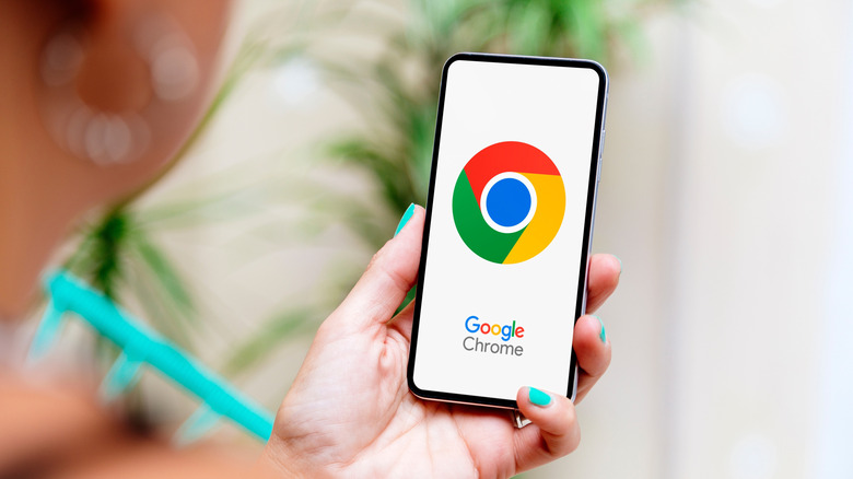 Google Chrome logo on a smartphone display in person's hands.