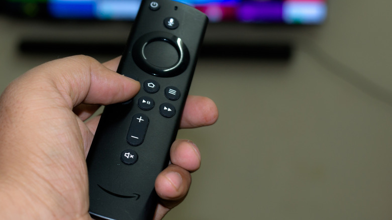 A Fire TV Stick remote being used to control tv functions