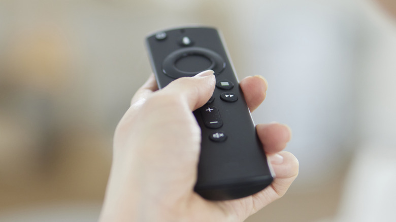 A Fire TV Stick remote in a person's hand
