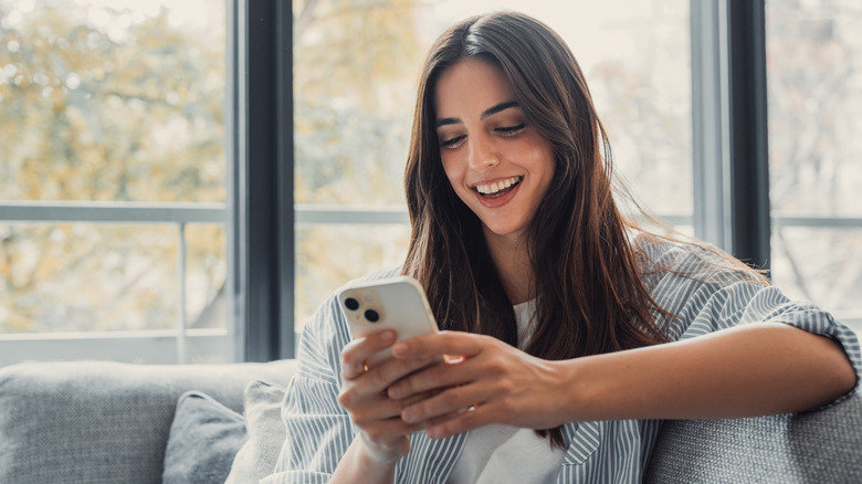 woman smiling and using her phone