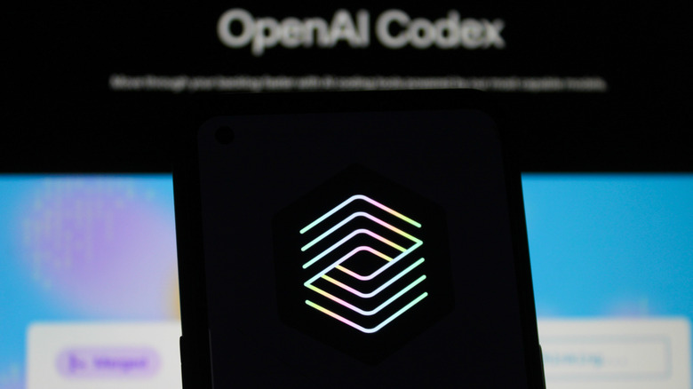A smartphone with the ChatGPT Codex logo in front of a blurry display that says "OpenAI Codex".