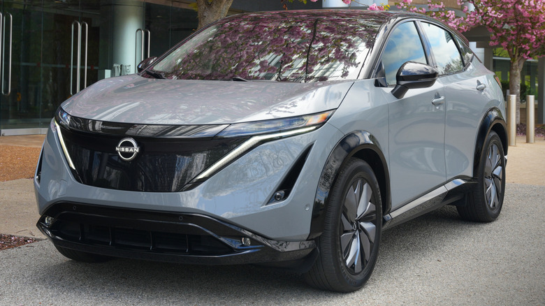 The Nissan Ariya standing in front of a tree with pink leaves