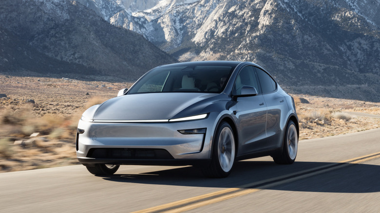The Tesla Model Y driving down a road overlooking some mountains