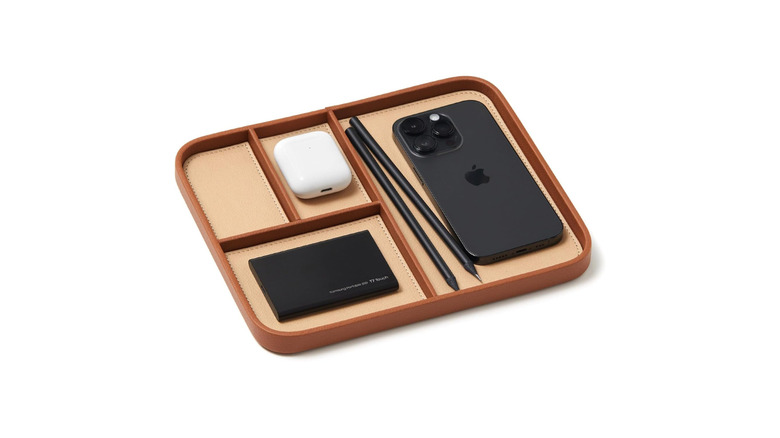 A tan vegan leather tray holding a number of Apple devices on white background