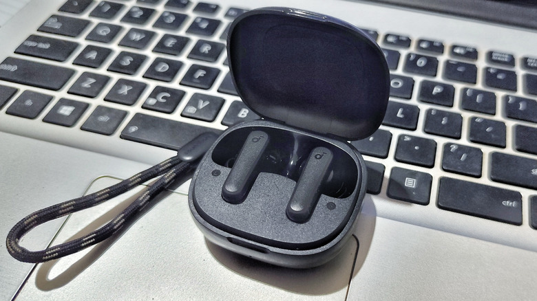 Some Soundcore earbuds, on a laptop keyboard.