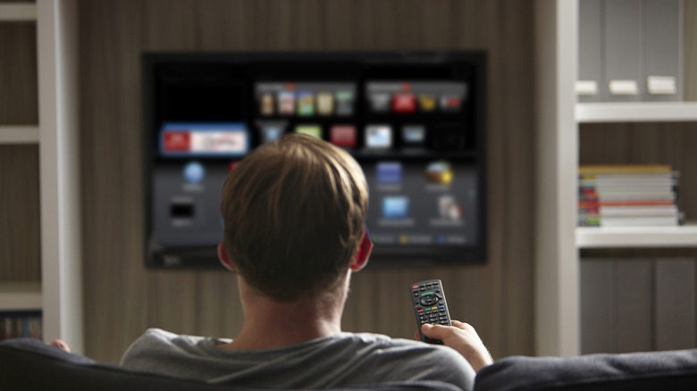 A man holding the remote control for a smart TV