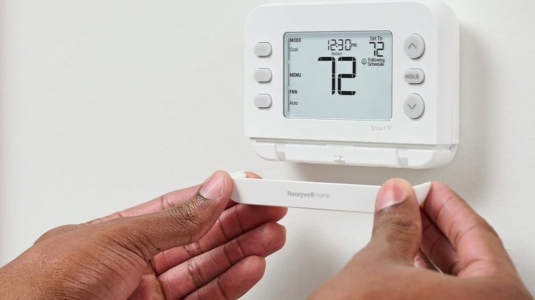 A person installing the bottom trim of the Honeywell Home Smart Thermostat.