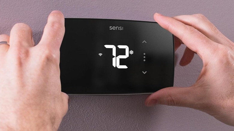 A person installing the Sensi Lite Smart Thermostat on a wall.