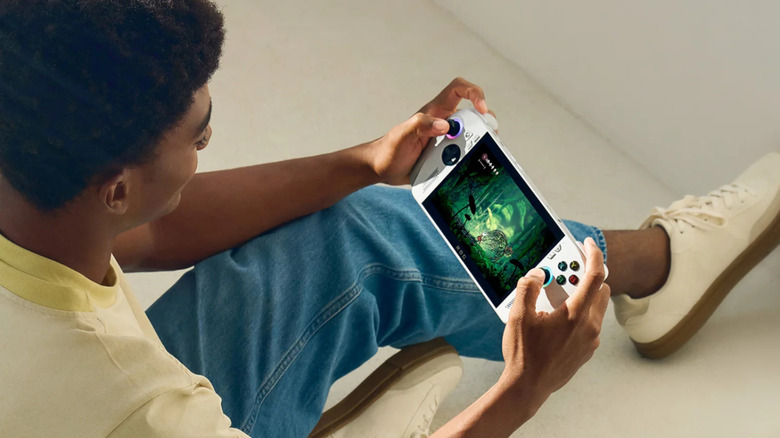 Person sitting on the floor while playing a game on the Asus ROG Xbox Ally handheld.