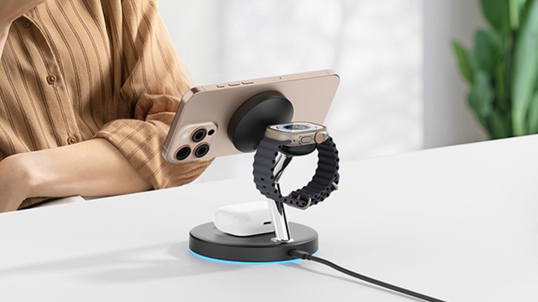 The Ouotoo 3-in-1 Charging Station with Magsafe sitting on a white table, the accessory is holding an iPHone, AirPods, and an Apple Watch Ultra