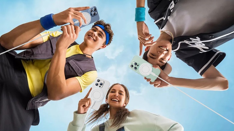 Three young individuals standing above the camera, each holding an iPhone that is attached to a white Tndaji 15W Magnetic Wireless Charger