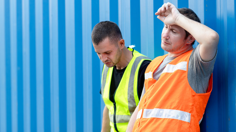 two men in construction worker vests outside in the heat