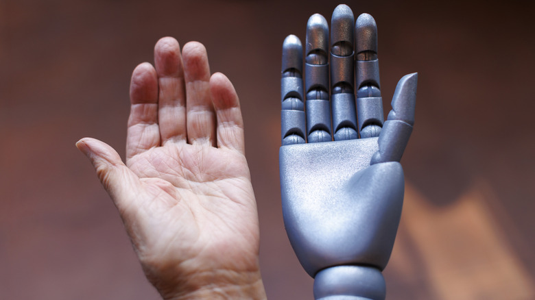 human and robot hands juxtaposed