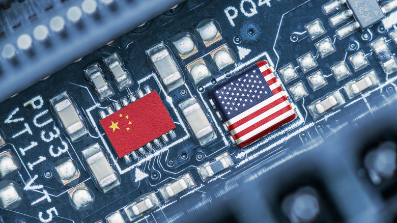 Flag of USA and China on a processor, CPU or GPU microchip on a motherboard. US companies have become the latest collateral damage in US - China tech war. US limits, restricts AI chips sales to China.