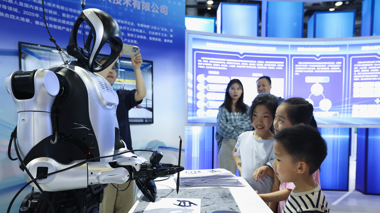 A humanoid robot demonstrates calligraphy at a technology convention.