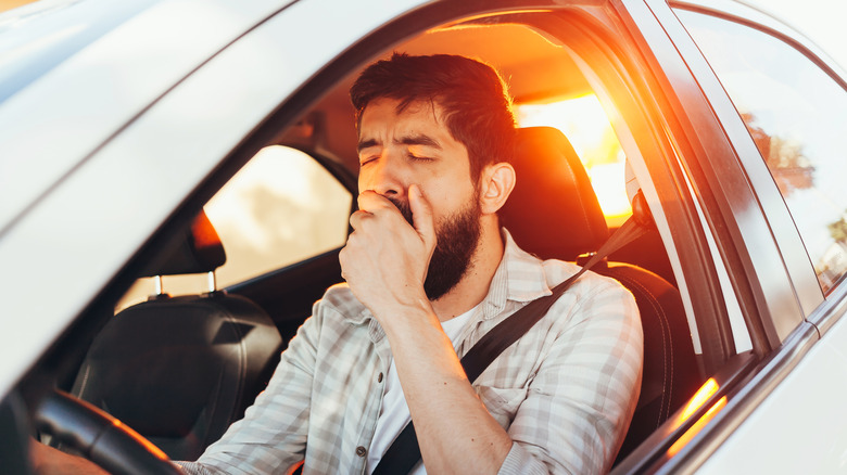 person yawning while driving car
