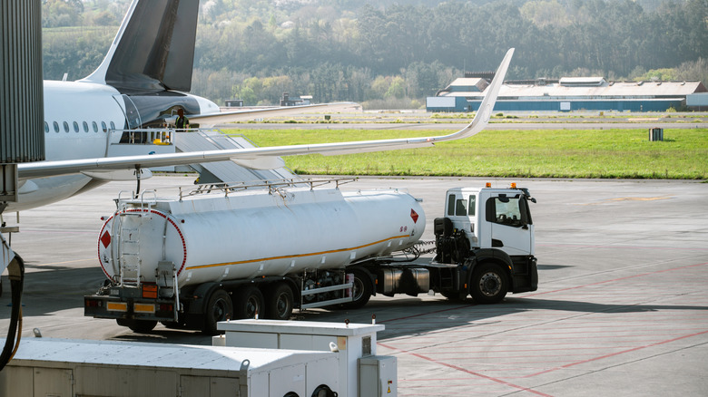 Fuel tanker refueling airplane on an airport tarmac