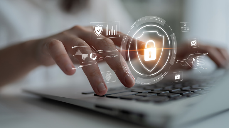 Close up of hands typing on a keyboard behind cybersecurity-related icons like a lock and a fingerprint