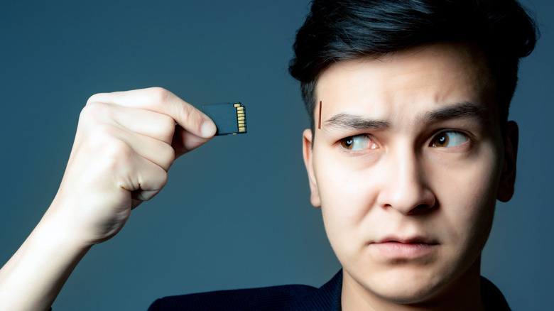 A man about to insert an SD card into a slot in his temple