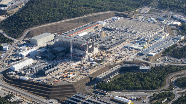 The International Thermonuclear Experimental Reactor campus is under construction, surrounded by a forest and empty roads.